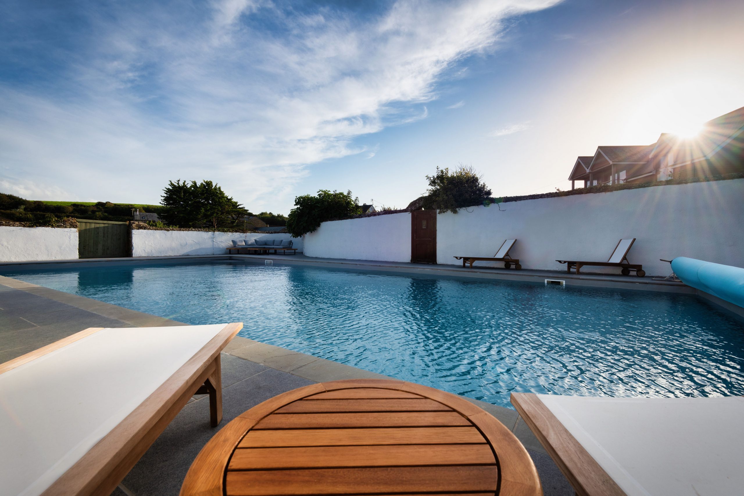 Outdoor swimming pool with loungers and country walls at The W Club, Whalesborough, Bude, Cornwall