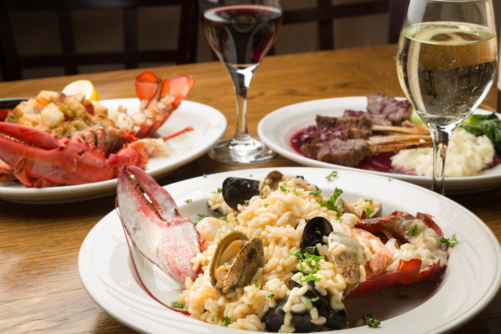 Lobster and Lamb chop Dishes arranged at a dinner table with wine